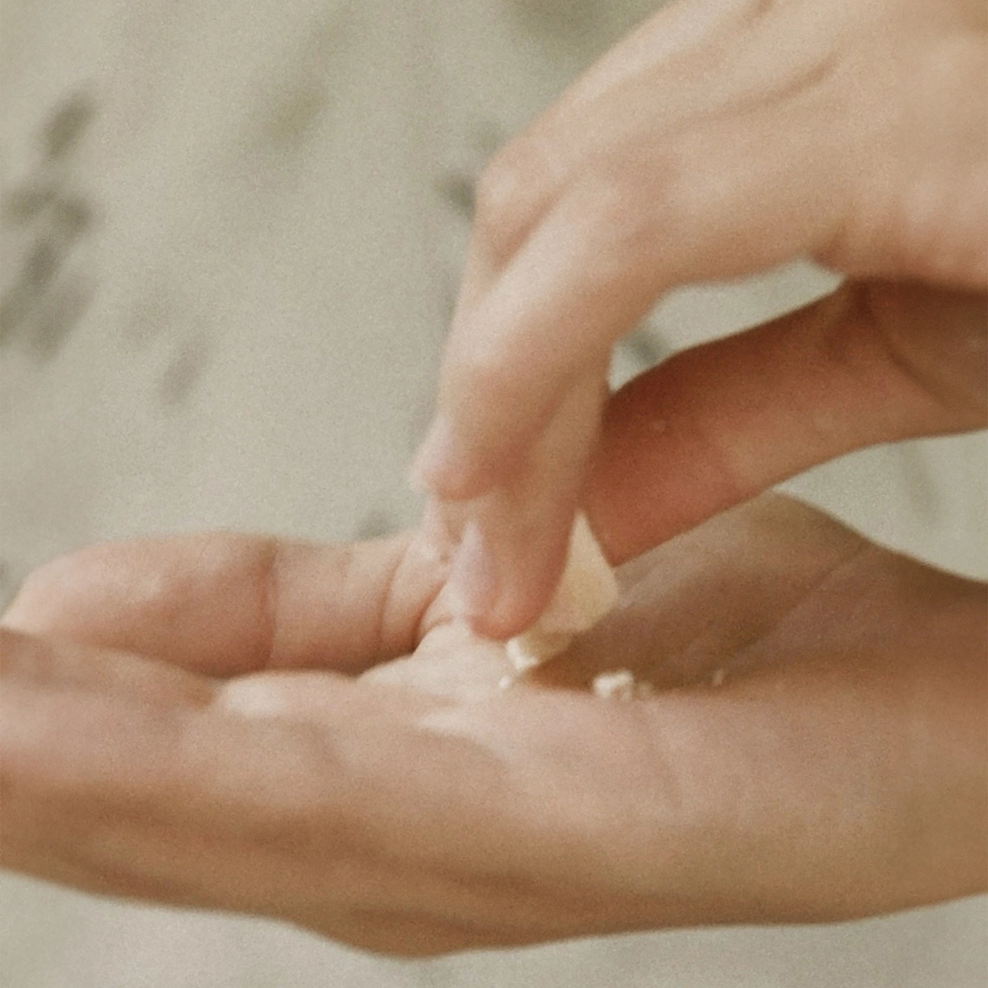 Close-up of hands crumbling a Blu & Green Daily Conditioner tablet in the palm.