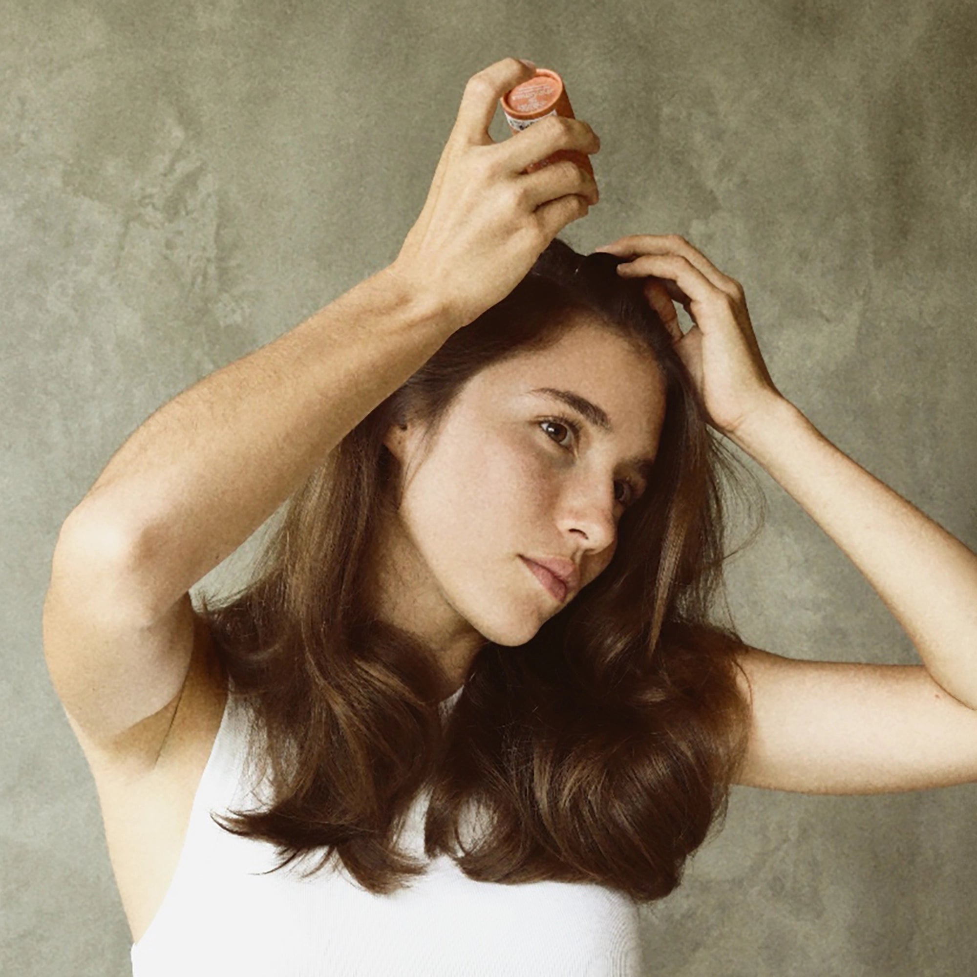 Woman applying Blu & Green dry shampoo to the roots of her hair.