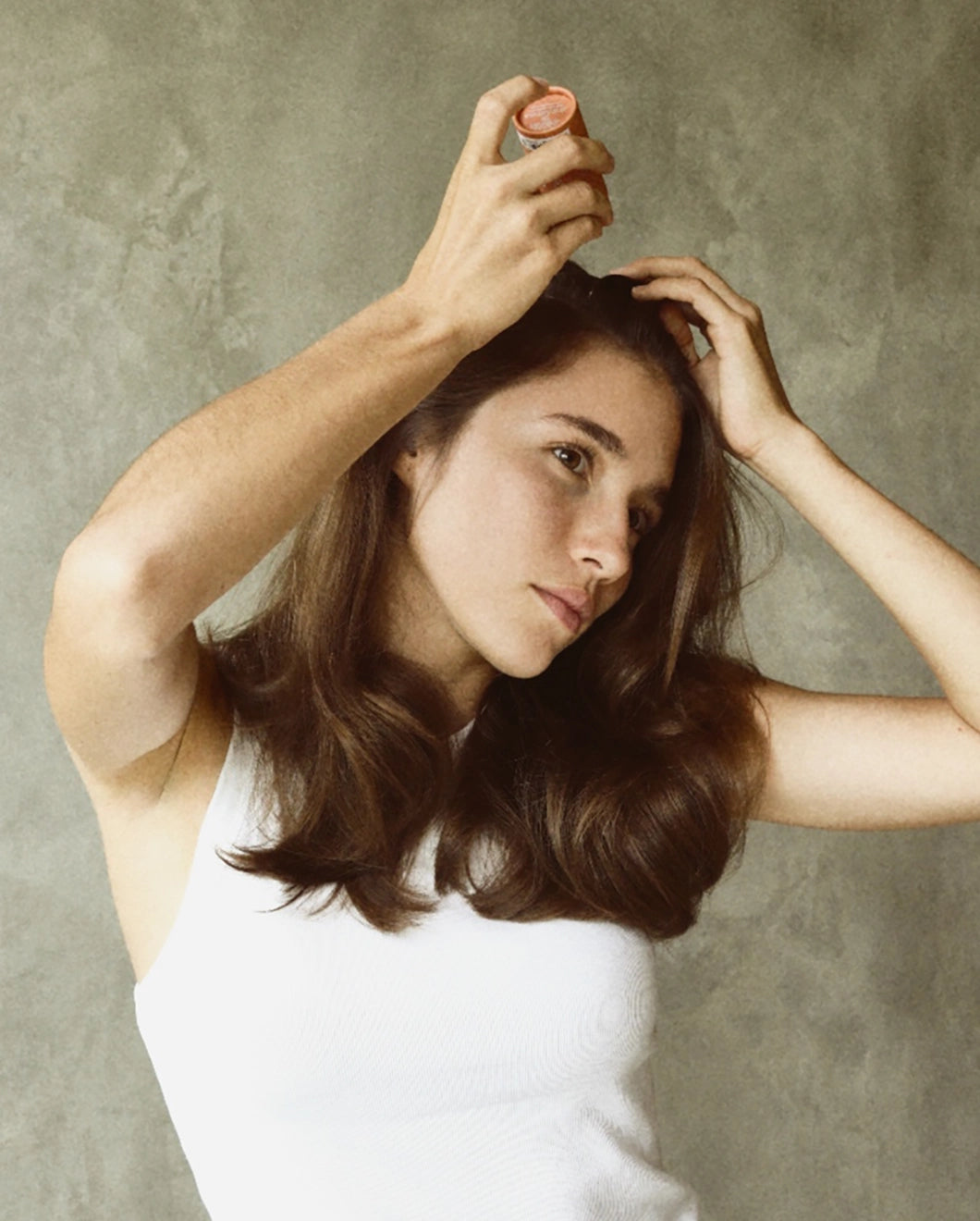Woman applying Blu & Green dry shampoo to the roots of her hair.