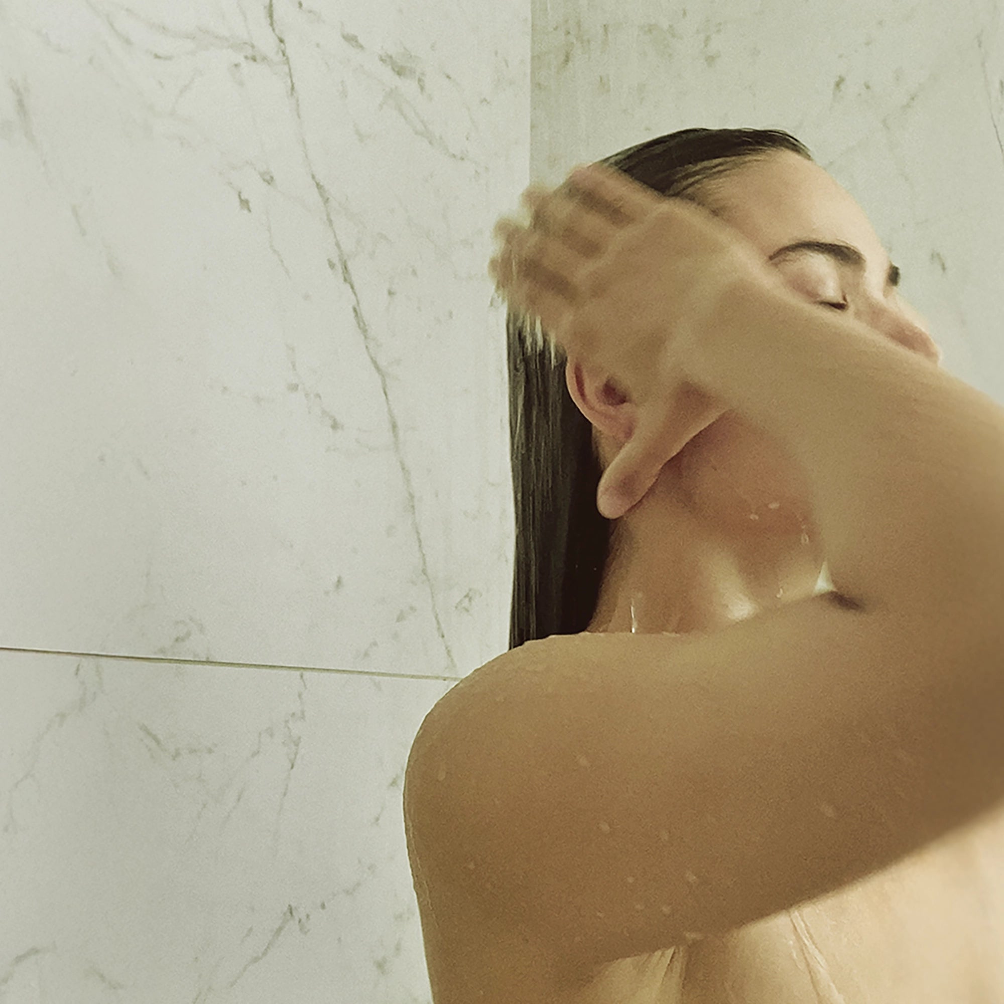 Woman rinsing Blu & Green Conditioner Concentrate out of hair in the shower