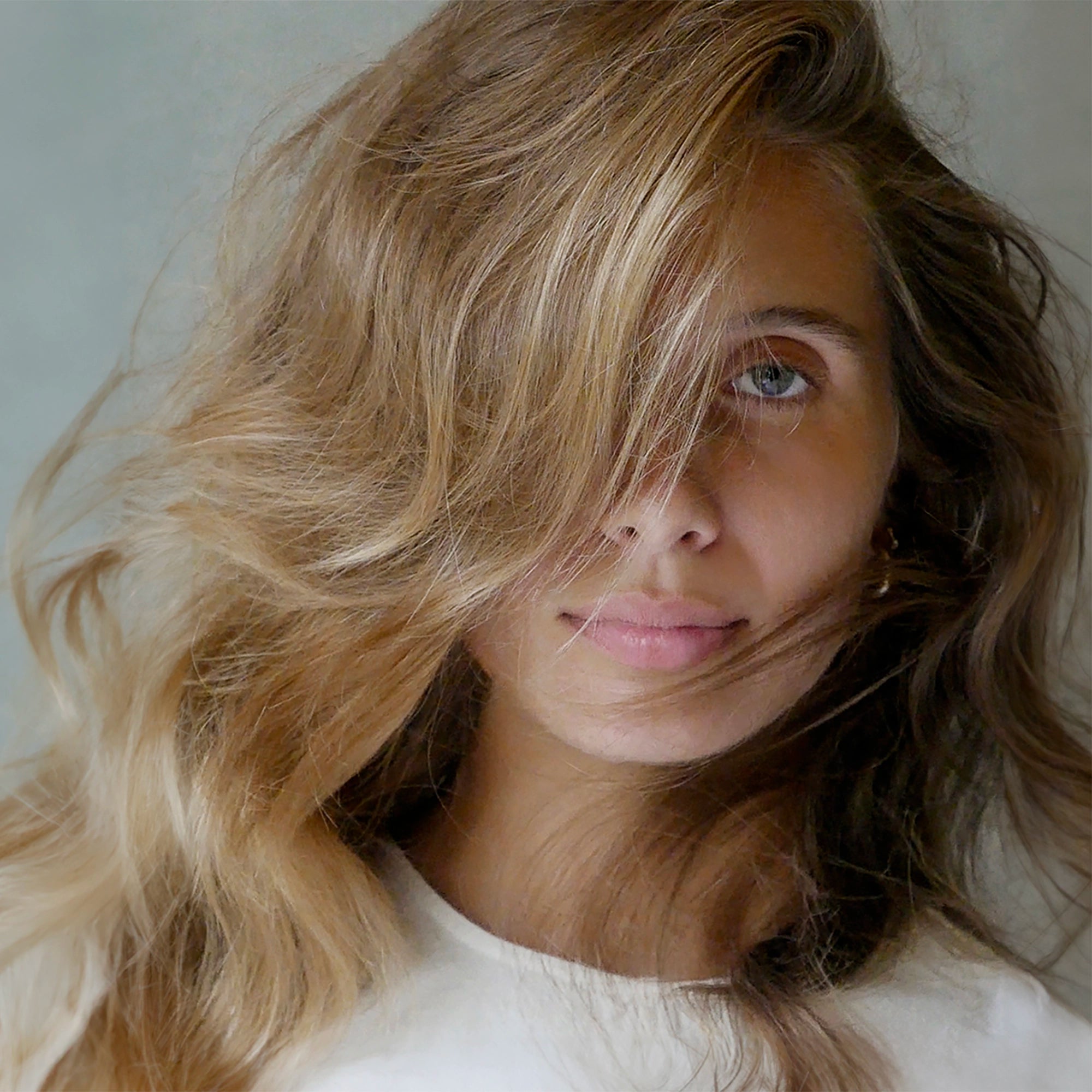 Portrait of a woman with long, wavy hair partially covering her face.