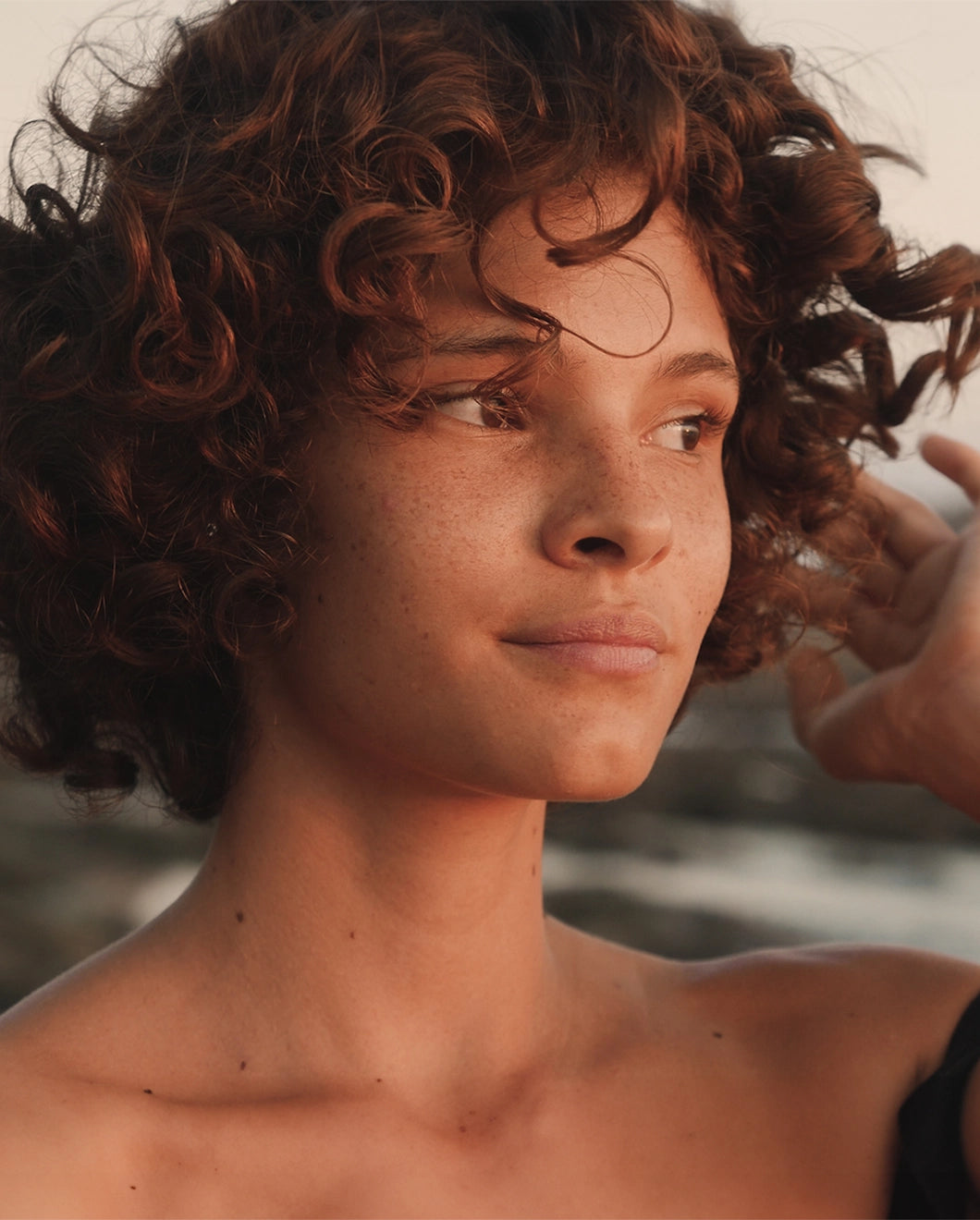 Woman with short, curly hair looking to the side.