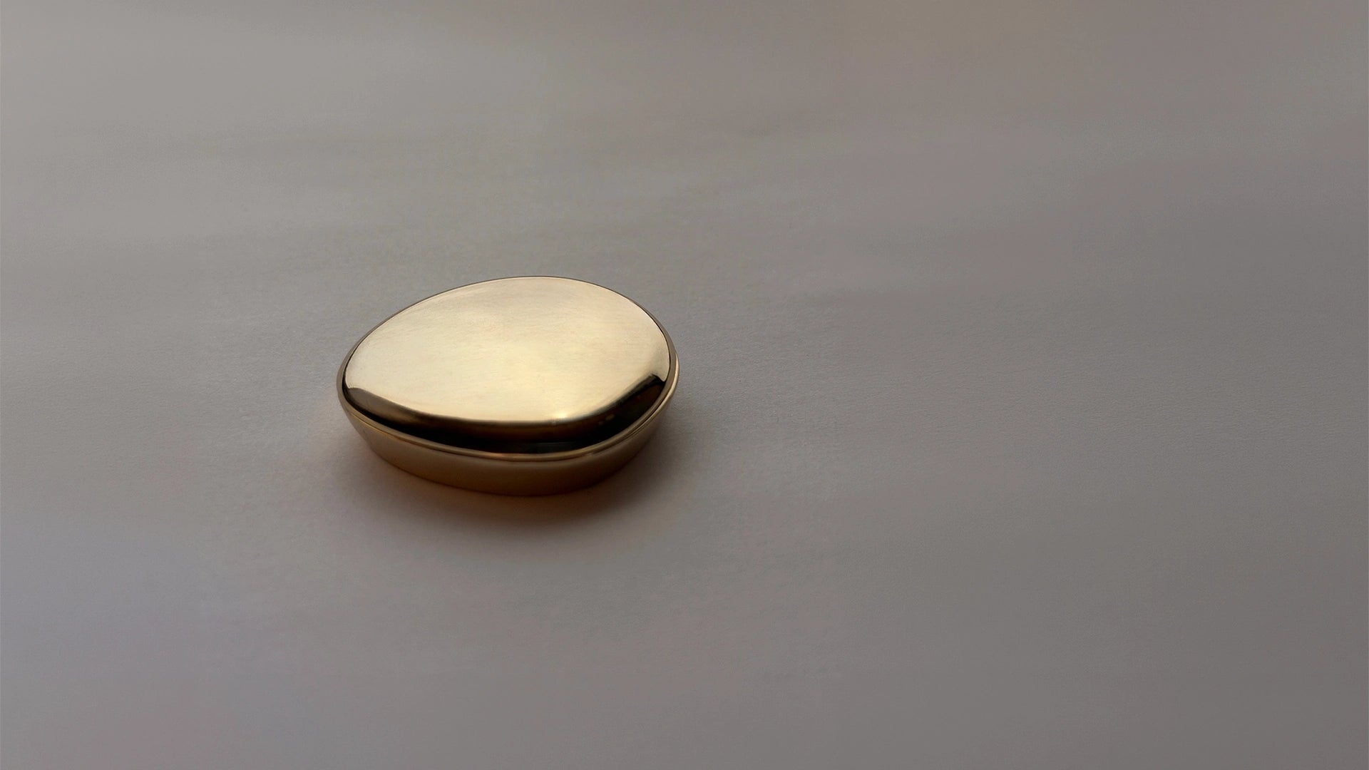 Blu & Green Juniper Dawn Solid Scent in a small, organically shaped, gold-colored metal case.
