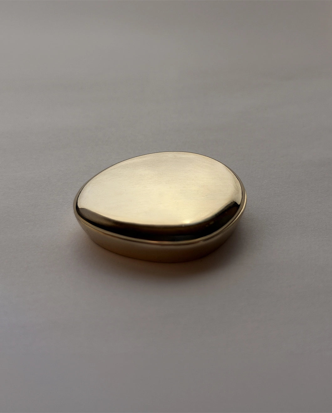 Blu & Green's Juniper Dawn Solid Scent . Packaging is a gold, pebble-like case.