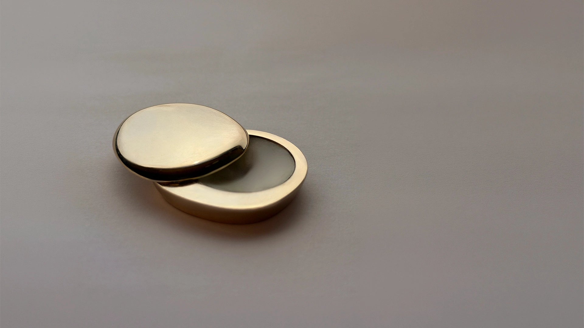 Blu & Green Juniper Dawn Solid Scent in a small, organically shaped, gold-colored metal case, slightly opened.