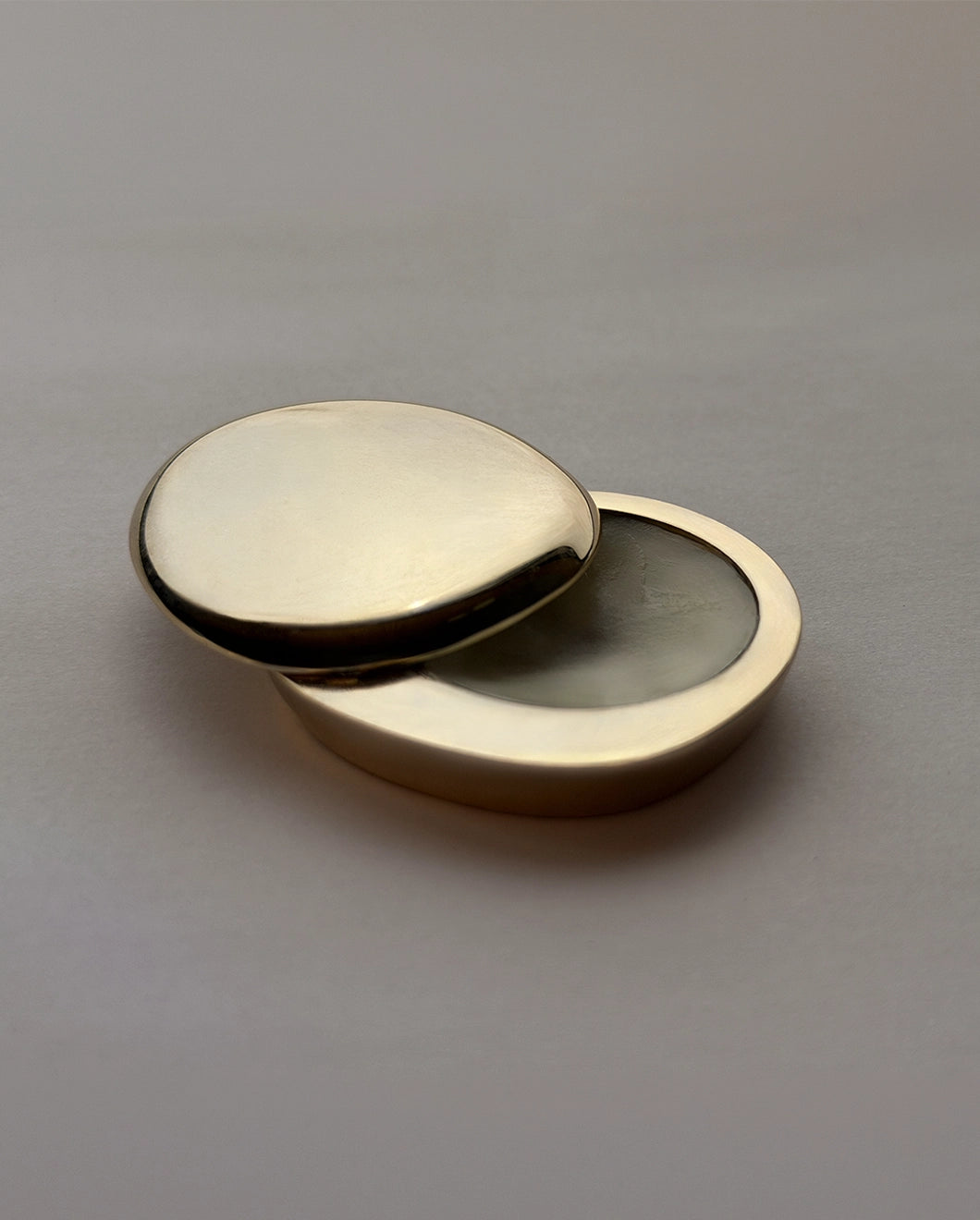 Blu & Green's Juniper Dawn Solid Scent gold, pebble-like case, slightly open.