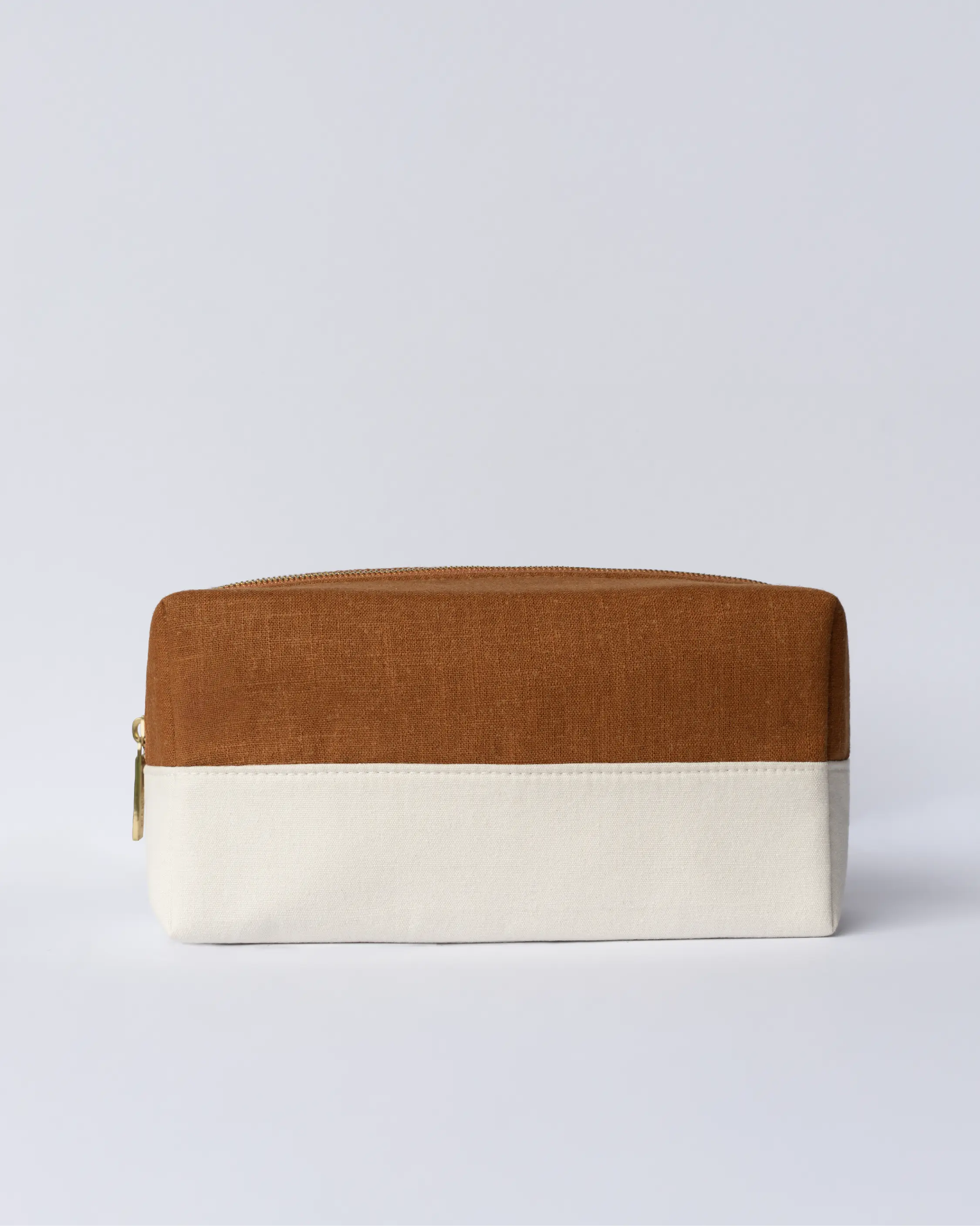Blu & Green's lightweight, durable Travel Bag, with a structured cotton canvas base, layered with a burnt-orange linen top, and a custom metal zipper.