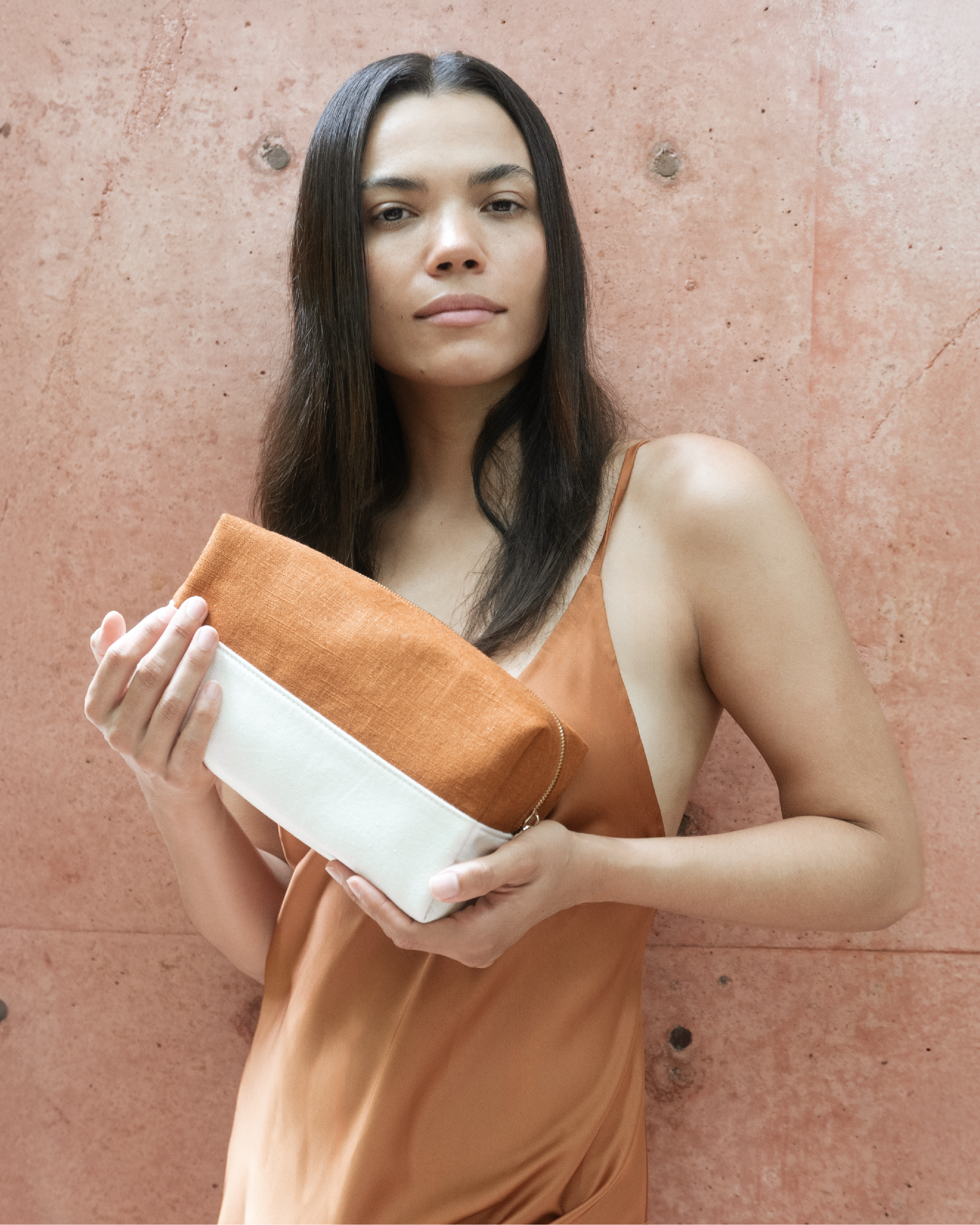 Woman holding Blu & Green's lightweight, durable Travel Bag, made with a structured cotton canvas base, layered with a burnt-orange linen top, and custom metal zipper.