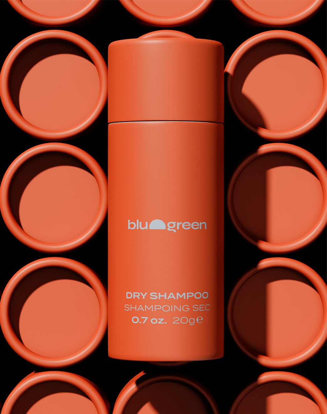 Blu & Green Dry Shampoo, 20g orange bottle standing upright atop matching caps, aerosol-free eco-friendly hair powder.