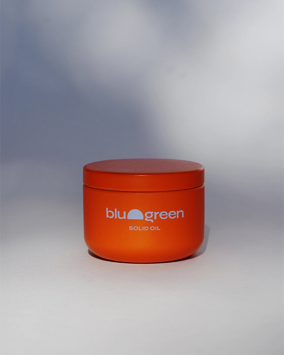Jar of Blu & Green Solid Oil hair balm photographed in soft natural light on a neutral background.