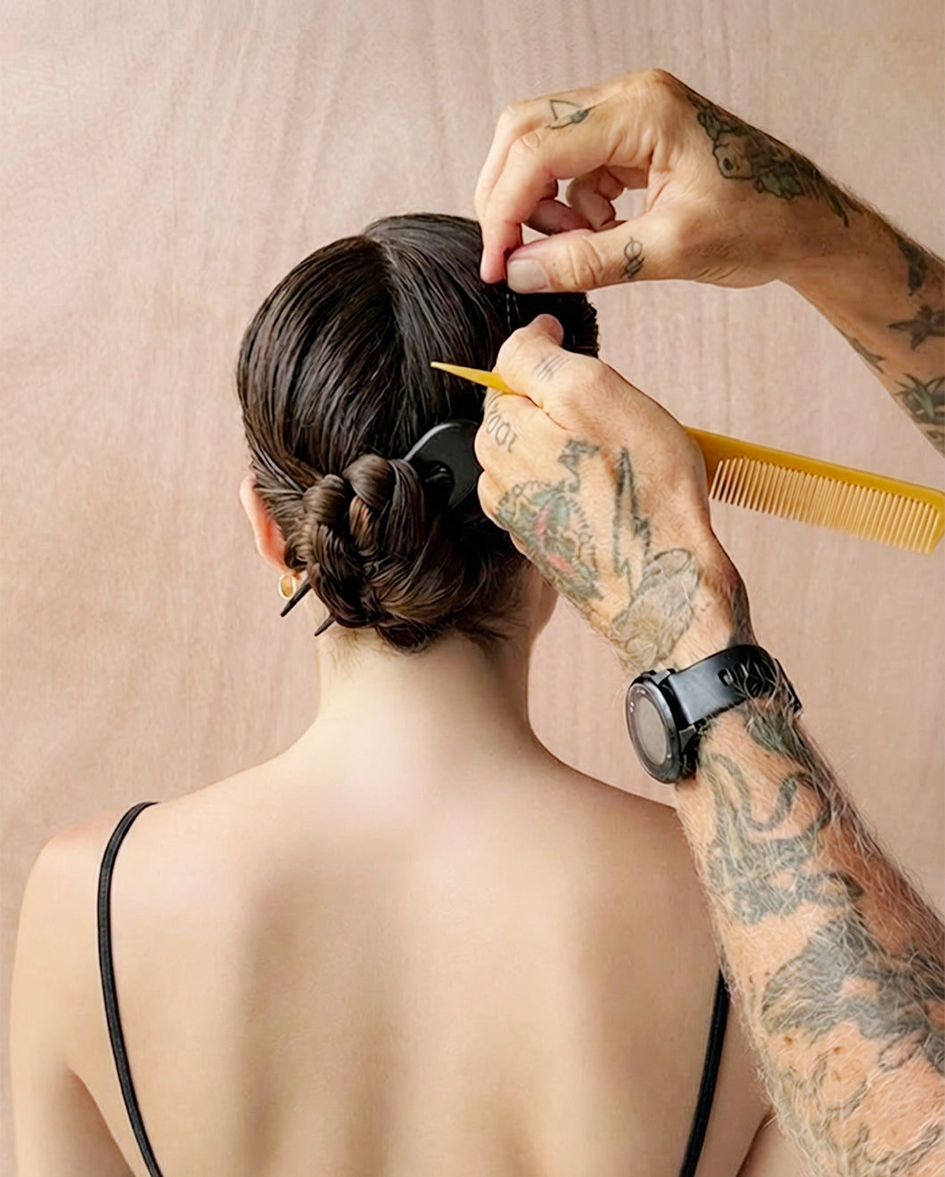 A close-up lifestyle shot of hairstylist James Pecis securing a hairstyle using the Blu & Green black, oversized, wooden hairpin.