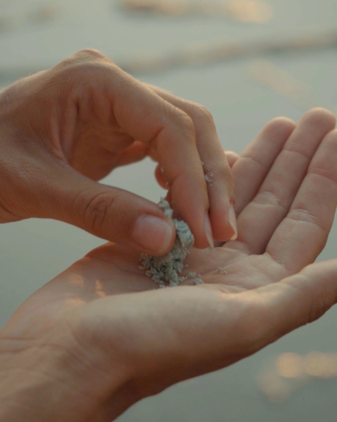Hand crumbling a travel-friendly Blu & Green Daily Shampoo Tablet into their hand.