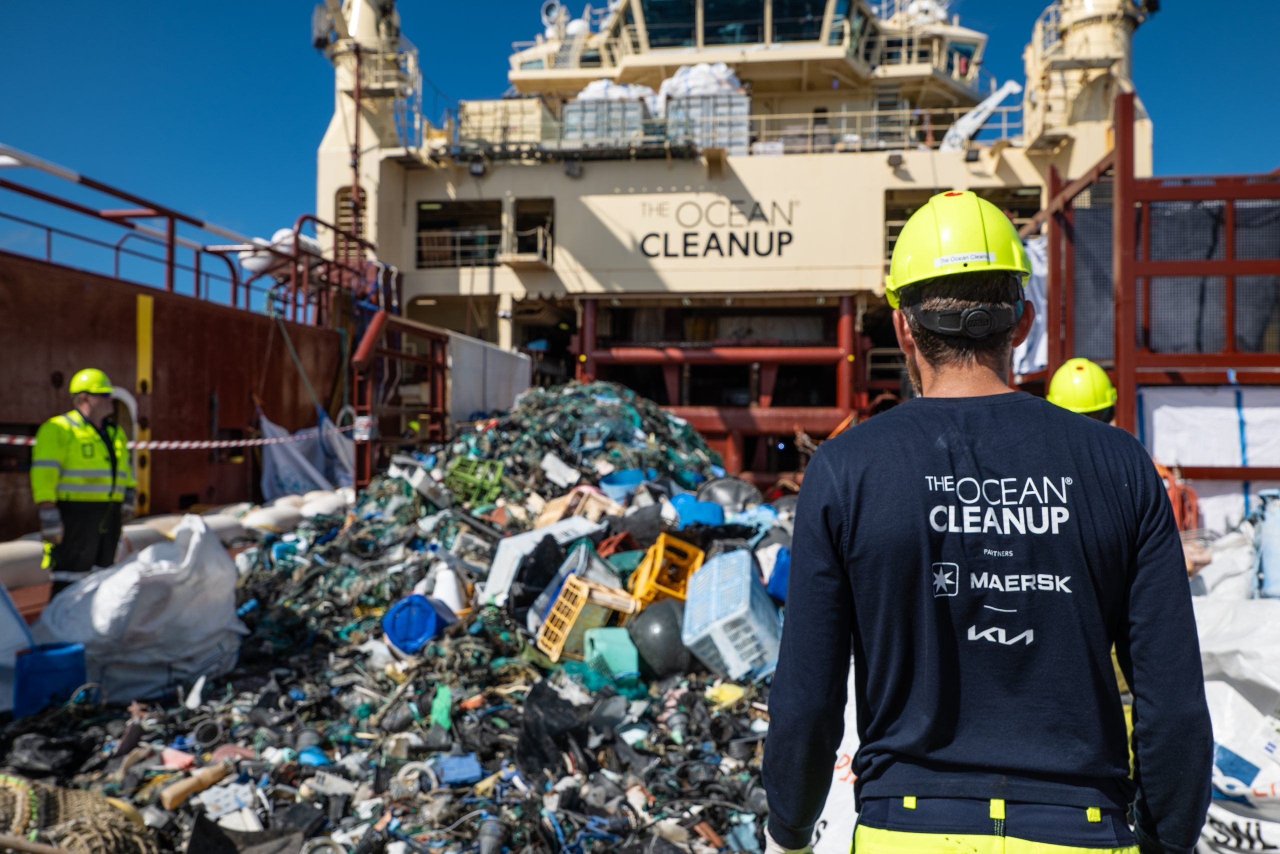 A photo of people working for the organization The Ocean Cleanup, on a barge collecting ocean plastic to remove and sort. 