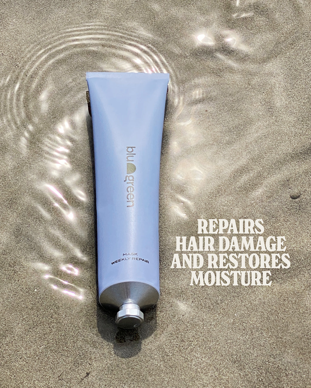 Blu & Green Weekly Repair Mask on sand with overlaid text reading “Repairs hair damage and restores moisture.”