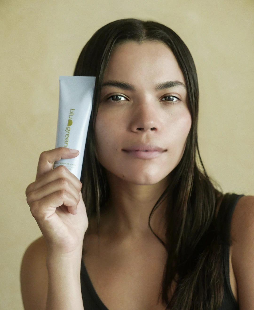 Woman holding a tube of Blu & Green Weekly Repair Mask.