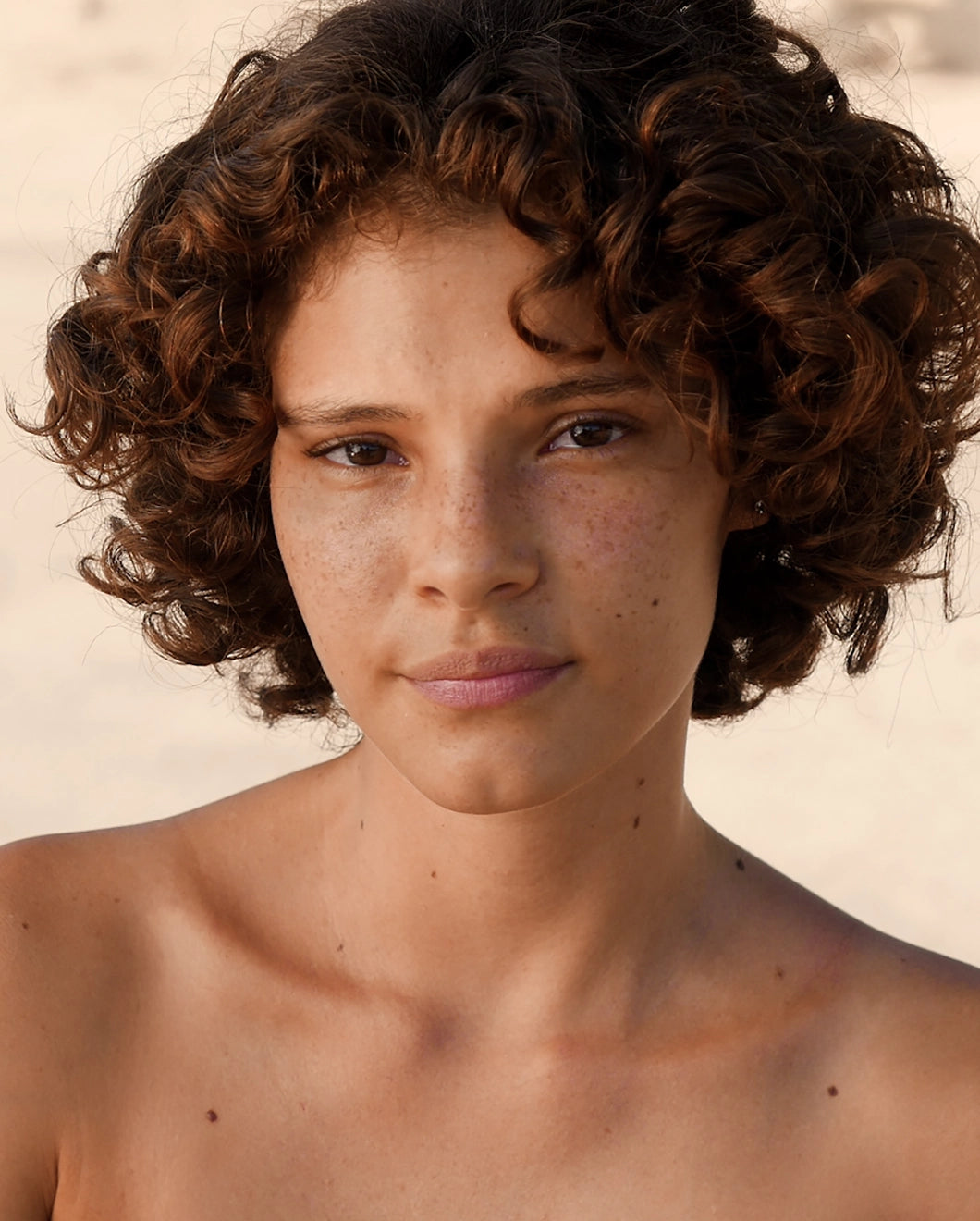 Portrait of a woman with short, curly hair looking at the camera.