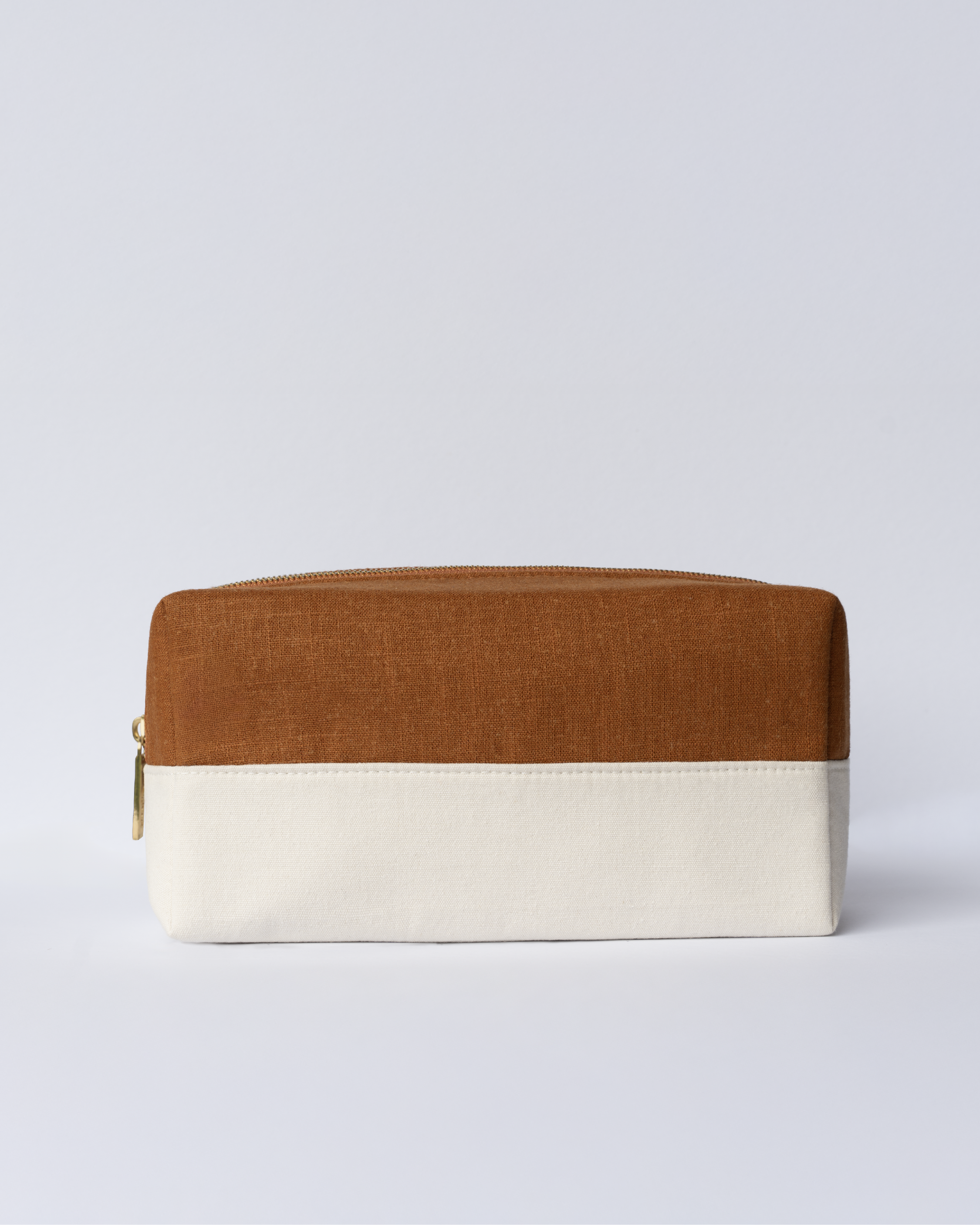 Blu & Green's lightweight, durable Travel Bag, with a structured cotton canvas base, layered with a burnt-orange linen top, and custom metal zipper.