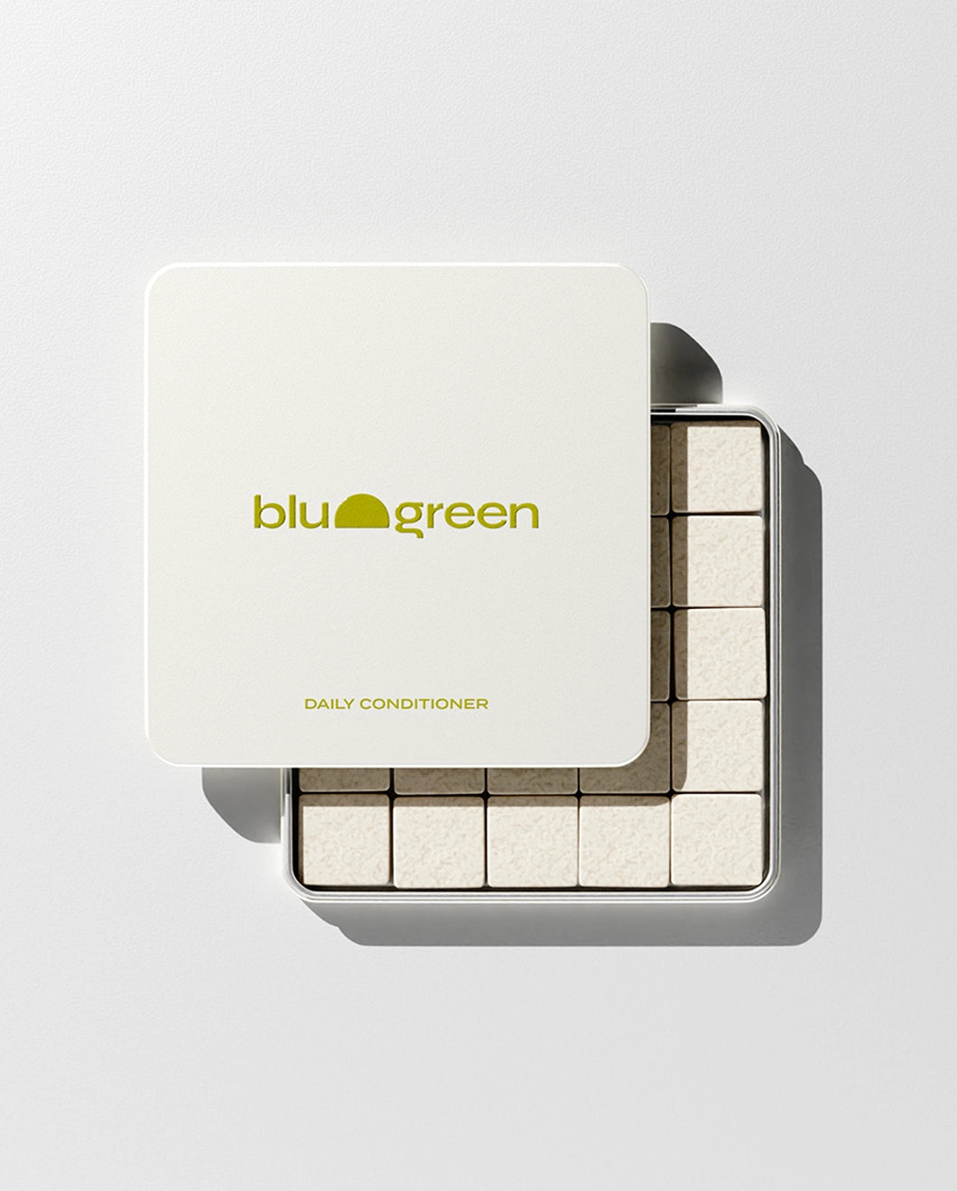 blu and green daily conditioner 50 cream-colored square tablets in a flat square tin with green-yellow logo. lid slightly off, studio, white ground, and strong light.