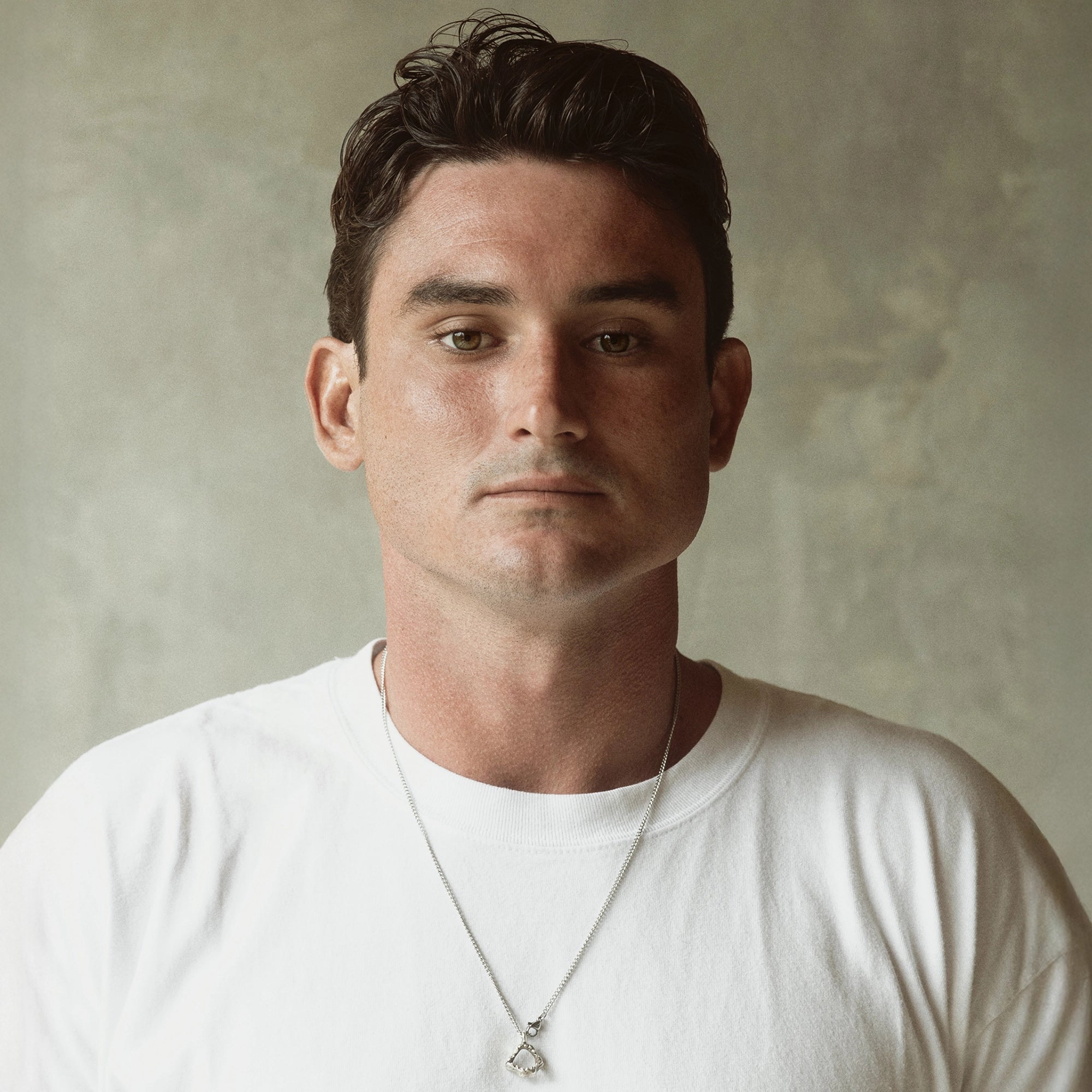 portrait of man with dark slicked-back hair styled with Blu & Green Solid Oil looking at the camera