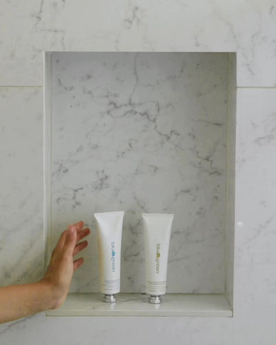 Woman in shower washing hair using Blu & Green's Daily Shampoo & Conditioner Concentrates.