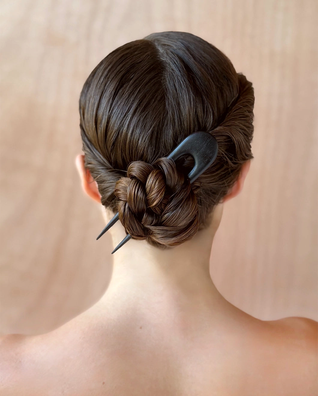 Back view of a person with dark brown hair styled in a low twisted bun secured with Blu & Green's black, oversized, wooden hairpin.